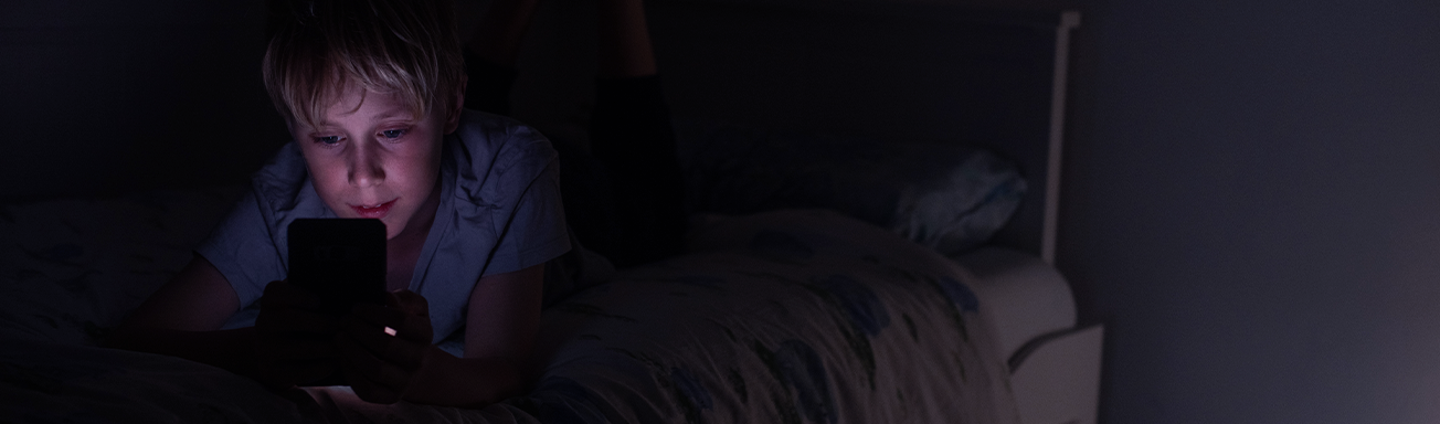 Young boy scrolling on phone in room alone in middle of night