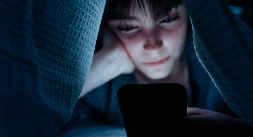 Girl scrolling on phone under the covers in the middle of the night