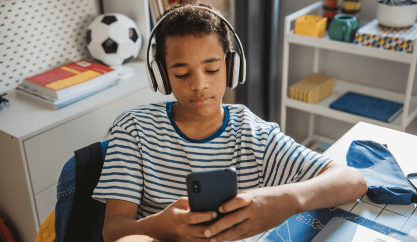 Young boy in his room scrolling on phone with headphones on watching short videos