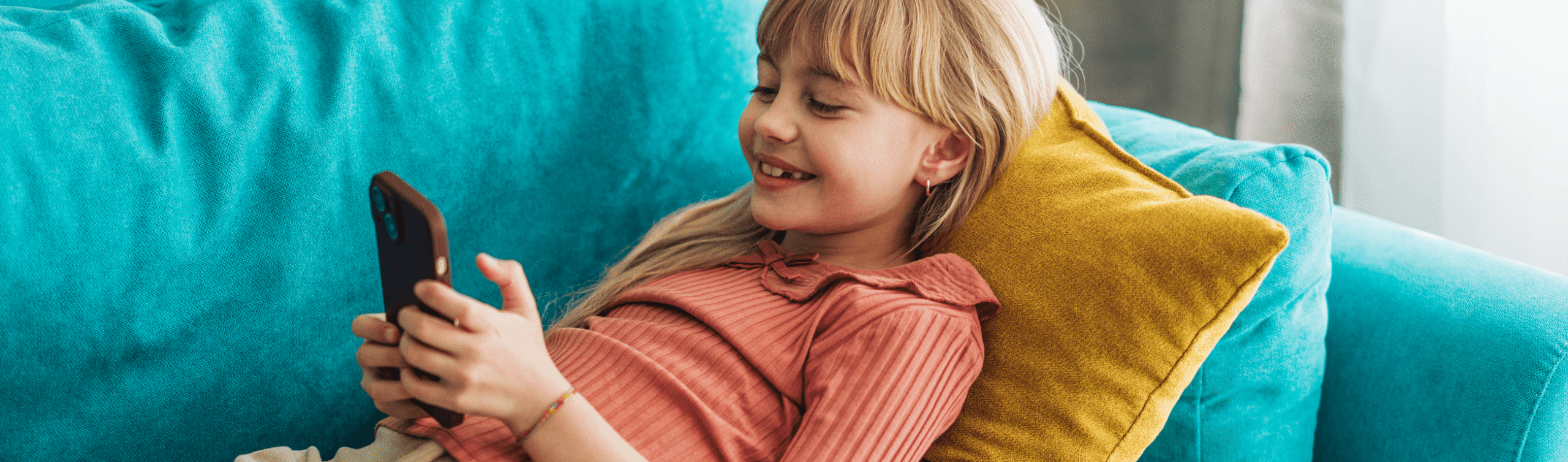 Young girl lying on sofa scrolling short videos on phone