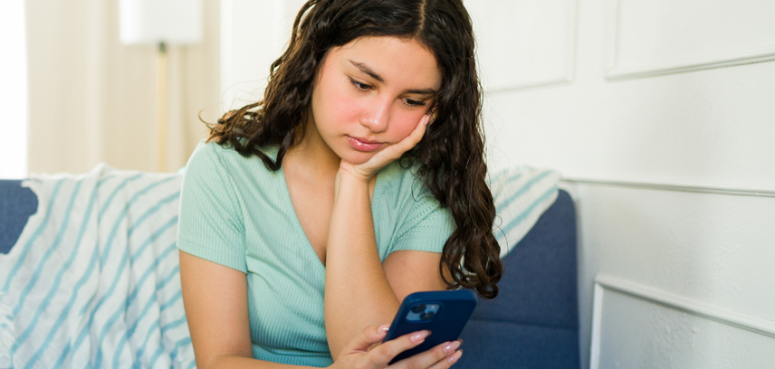 Worried teenage girl using smartphone