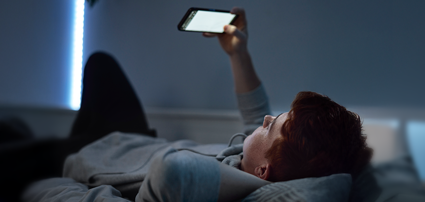 Teen boy using smartphone at night