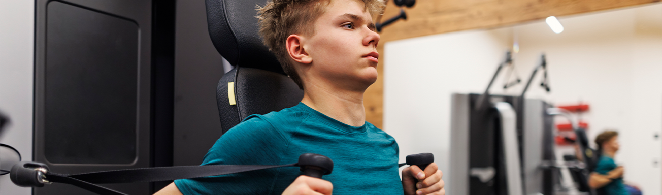 teenage boy working out and using machines at the gym